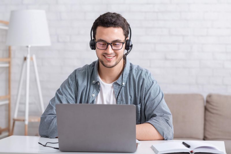 Kille med headset sitter vid sin dator och ger support via telefon